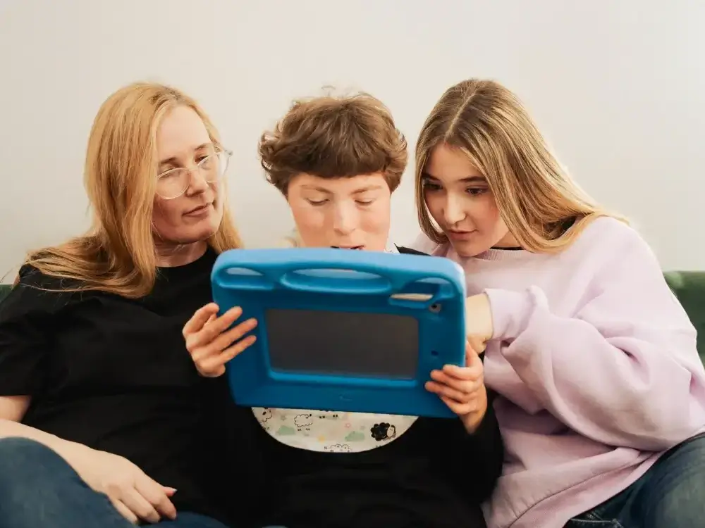 A mother and two sisters are looking at the Independo Calendar App on a talker.